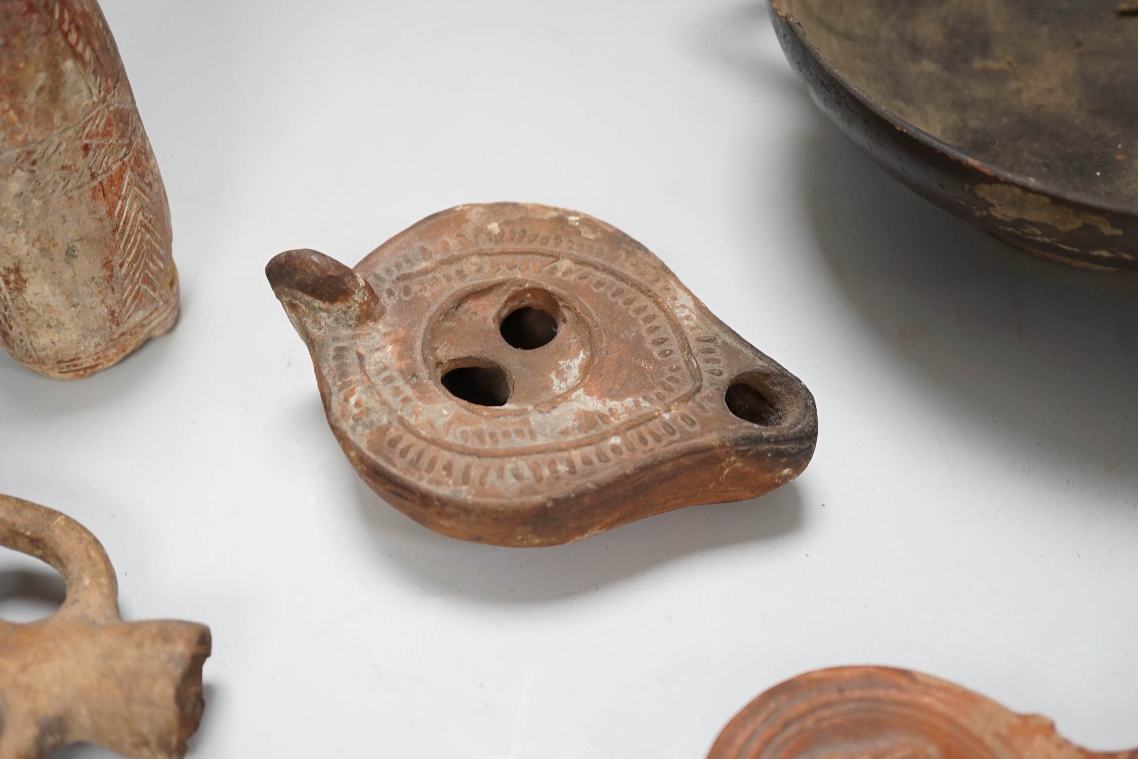 An Apulian black painted kylix, c. 4th century BCE., a Cypriot pottery flask, early Iron Age, two Roman terracotta oil lamps and another archaic vessel, tallest 14cm
